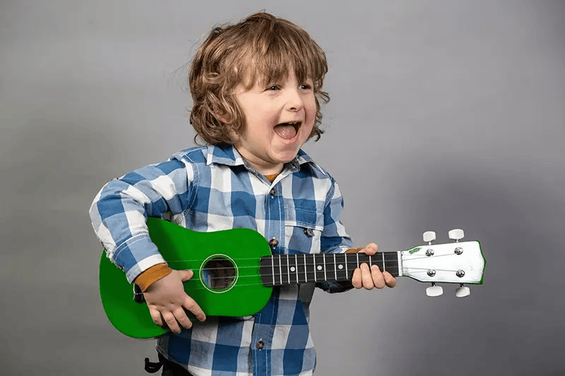 child with a
		smile holding a guitar